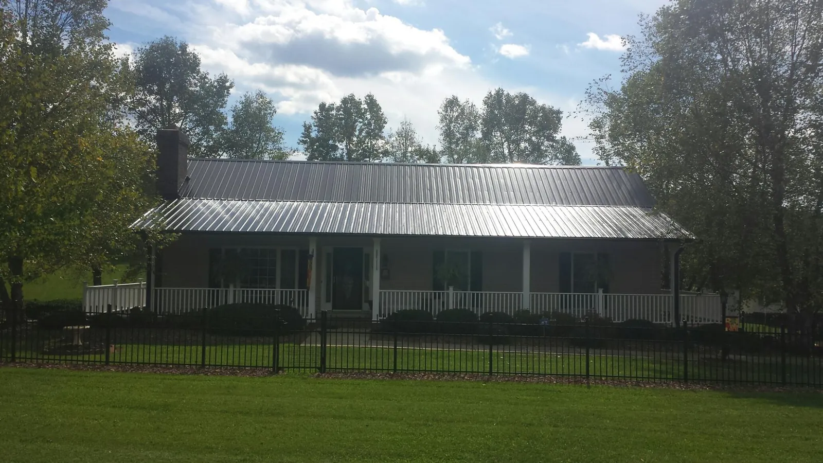 Gray metal roof on a brick ranch with a full width front porch — Gutter Guard Installation work by our crew in Gaffney