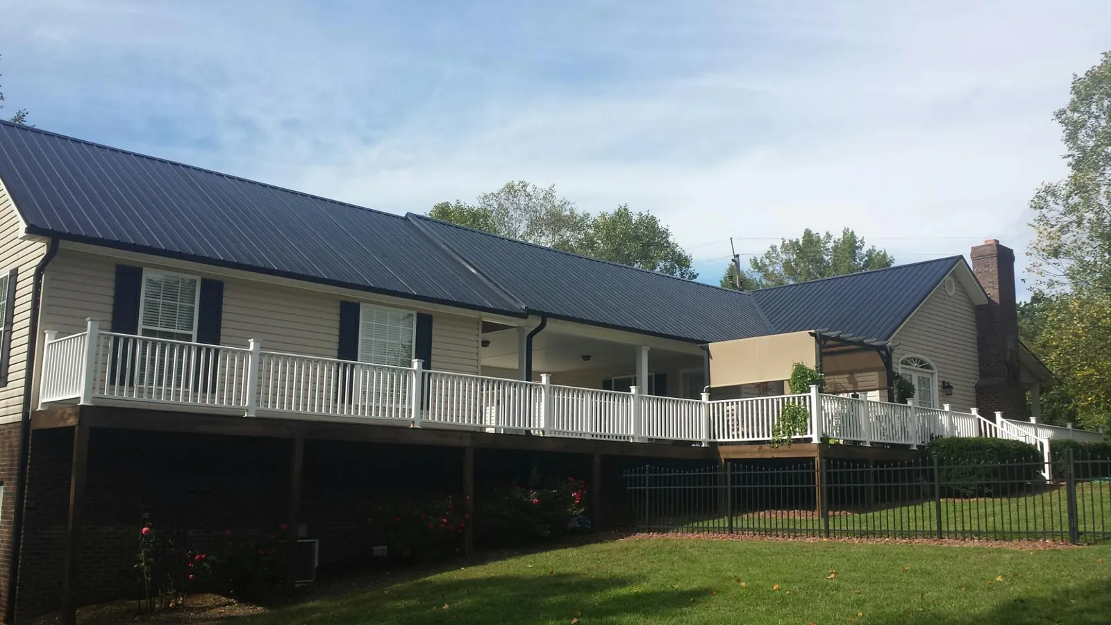 Black metal roof above a long white railed deck on a hillside home in Gaffney
