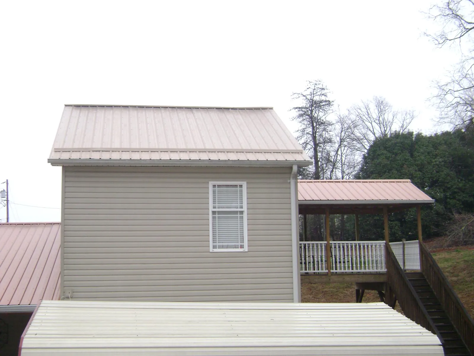 Tan metal roofs on a two story addition and attached porch, from a Roof Replacement job in Gaffney