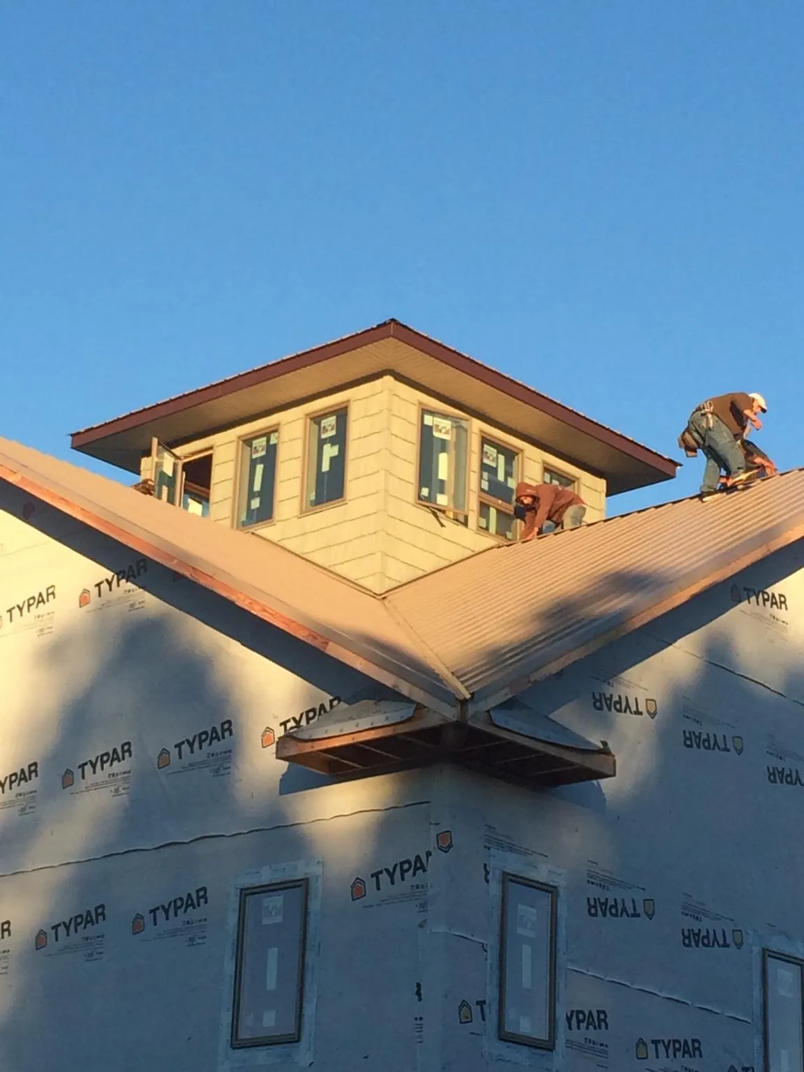 Roofers working around a rooftop cupola on a new metal roof at sunset — Roof Waterproofing in Gaffney by Roofing Brothers